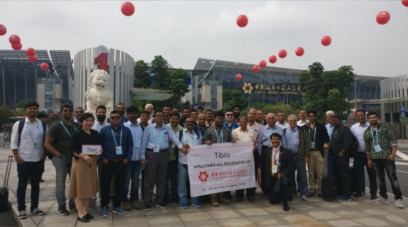 A group of people posing in front of a historic monument holding a banner.