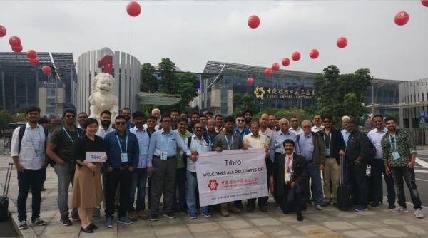A group of people posing in front of a historic monument holding a banner.