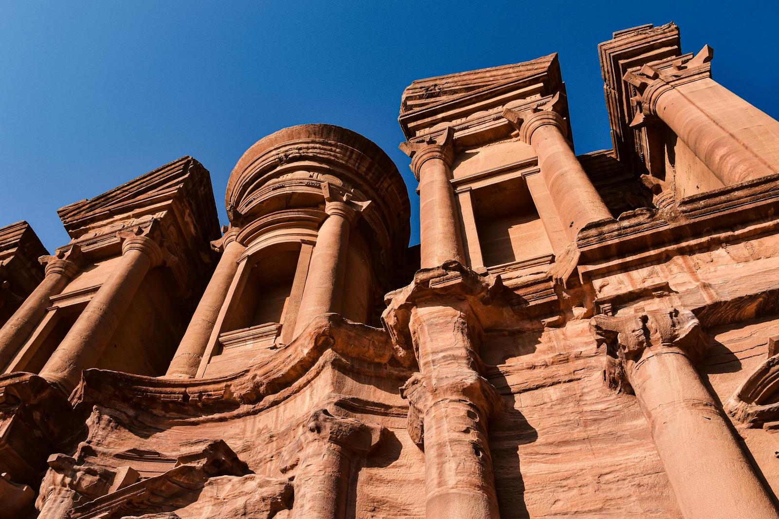 A low angle view of the sunlit columns of The Monastery in Petra, Jordan