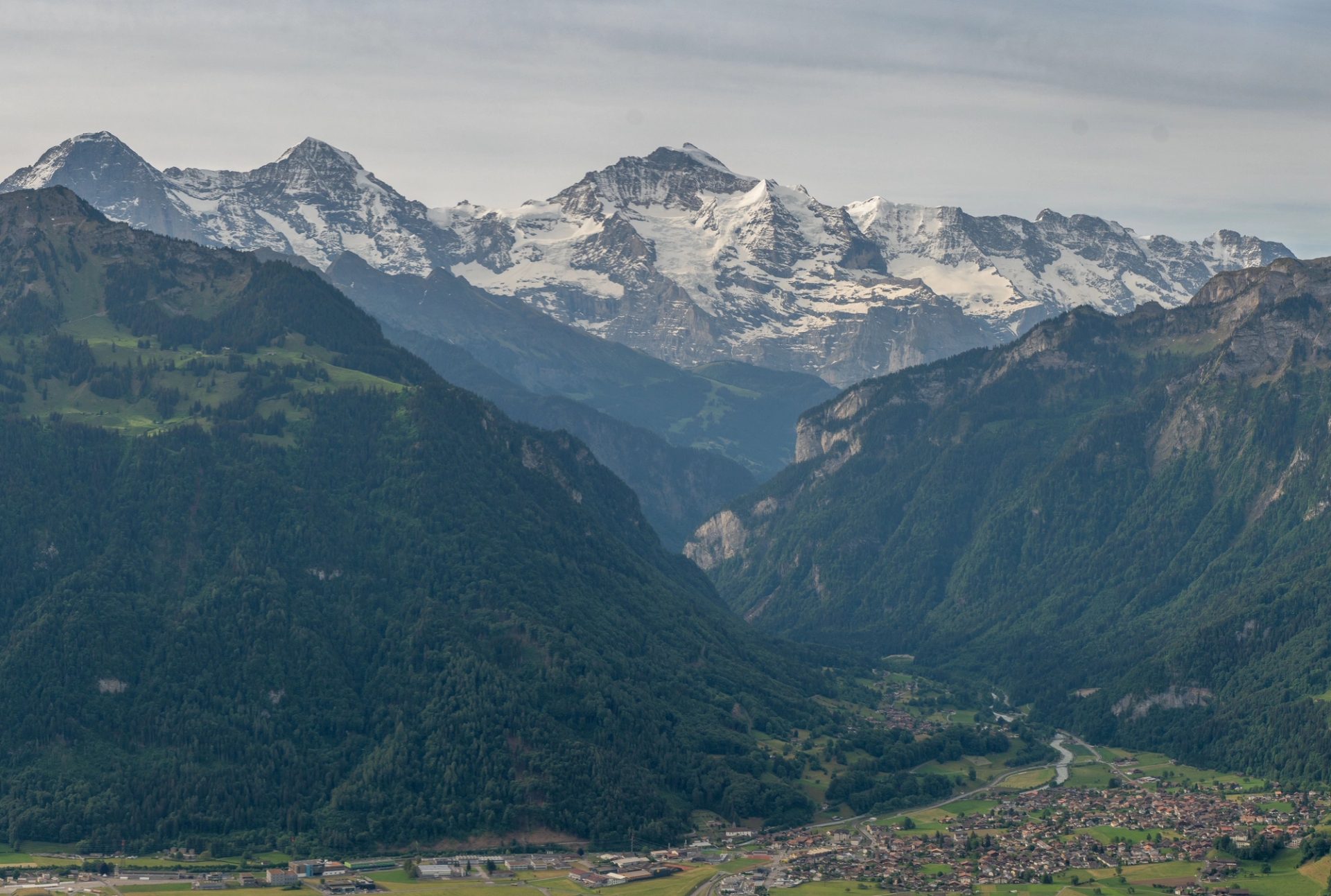 Scenic view of the Swiss Alps with lush green valleys and snow-capped peaks under a clear sky