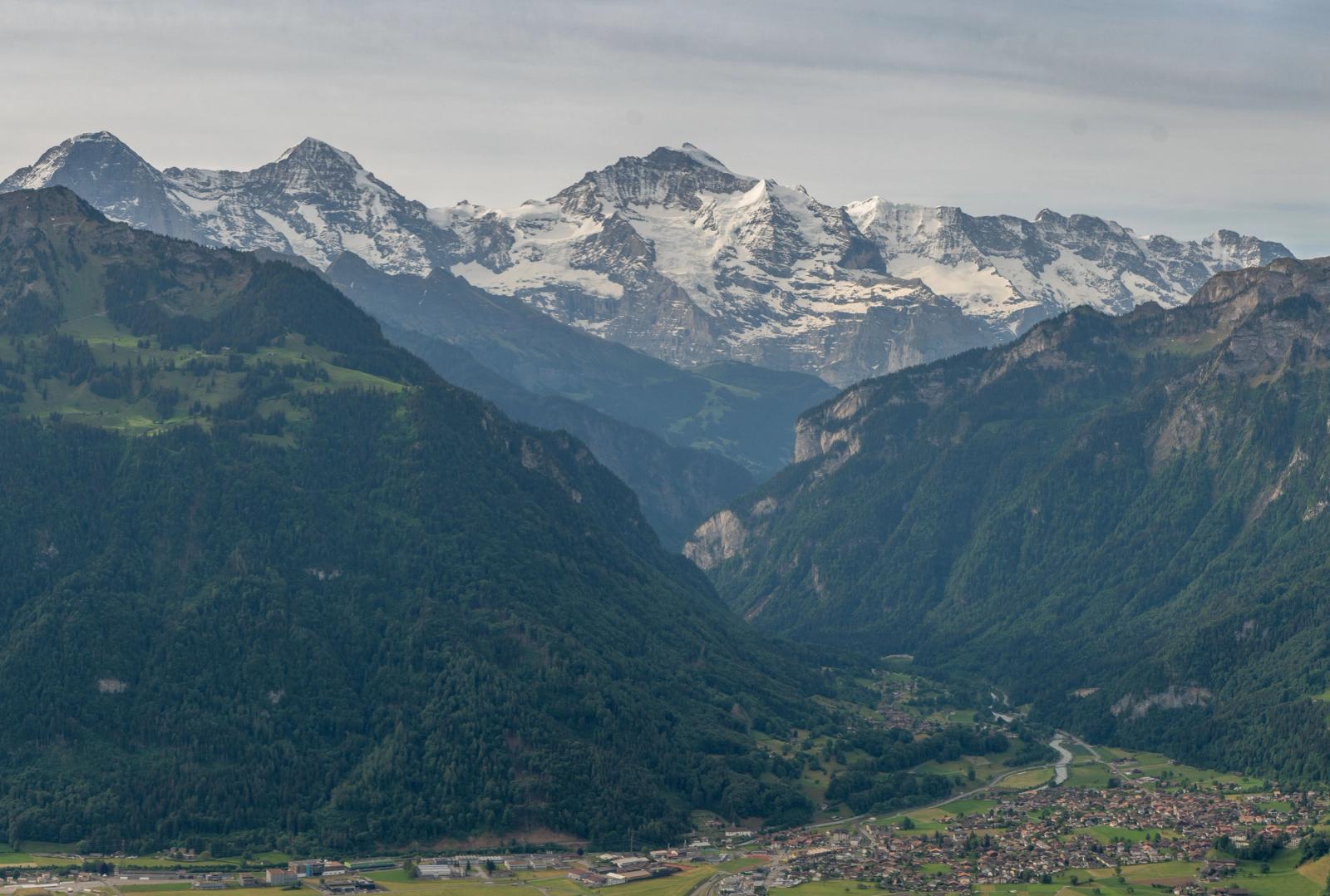 Scenic view of the Swiss Alps with lush green valleys and snow-capped peaks under a clear sky