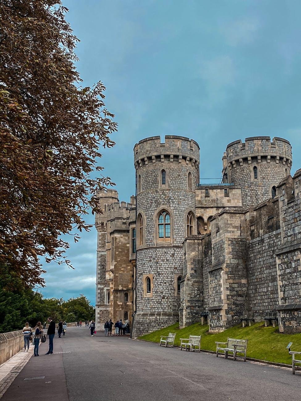Visitors walking past the turreted stone walls of a castle