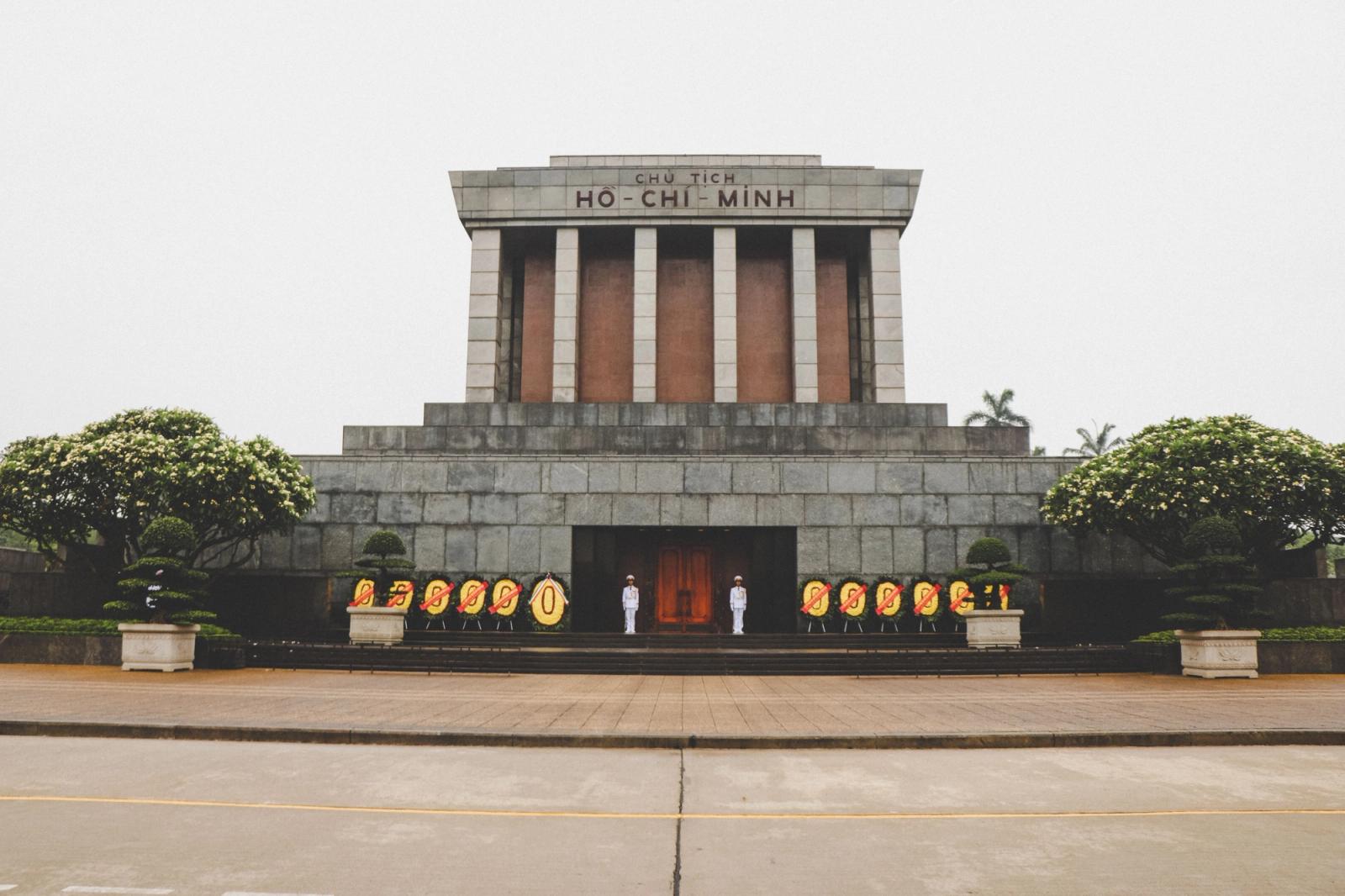 Front view of the iconic Ho Chi Minh Mausoleum in Hanoi, Vietnam with guards and floral wreaths