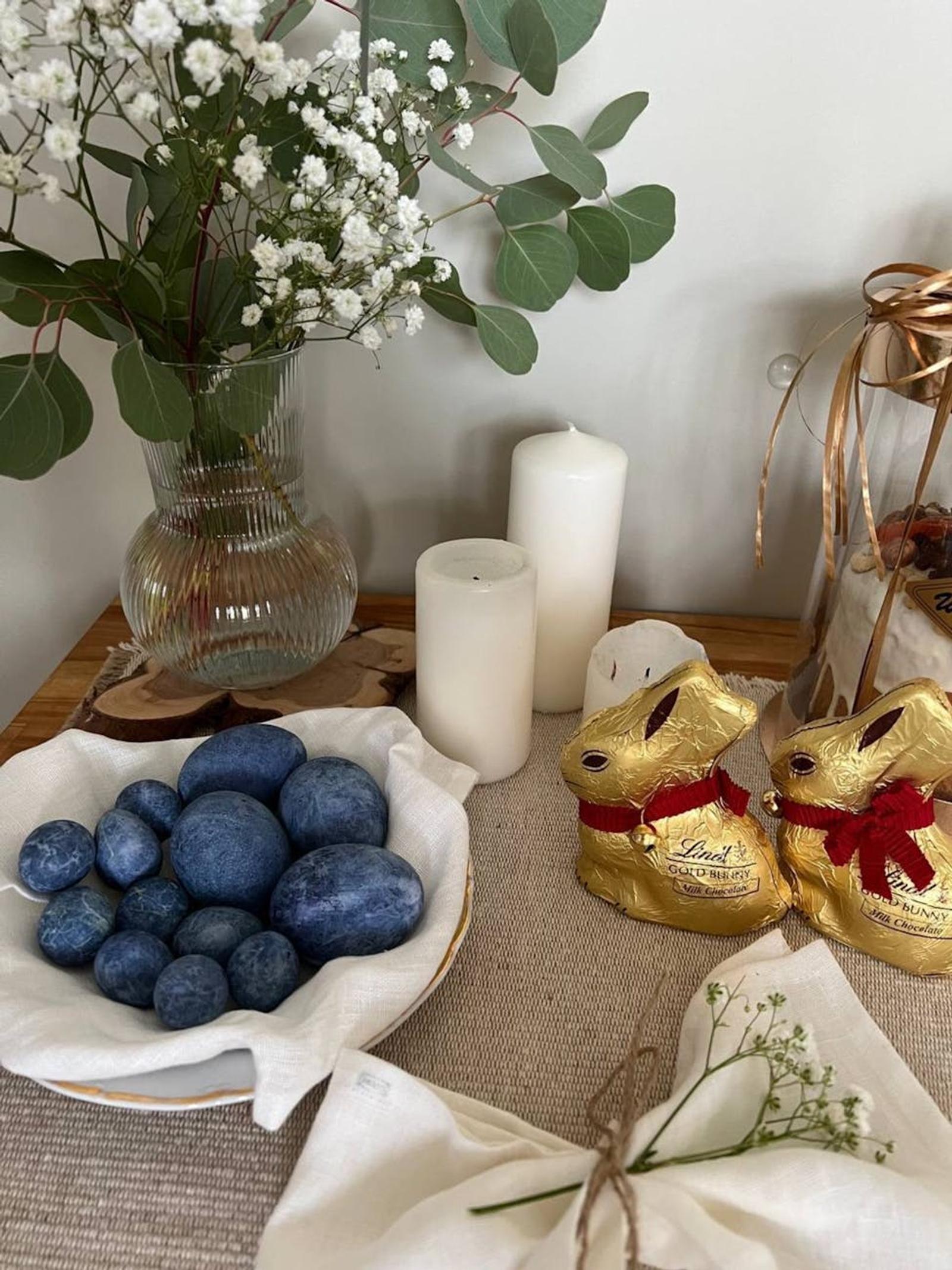 Decorative Easter setup with eggs, candles, and chocolate bunnies on a table