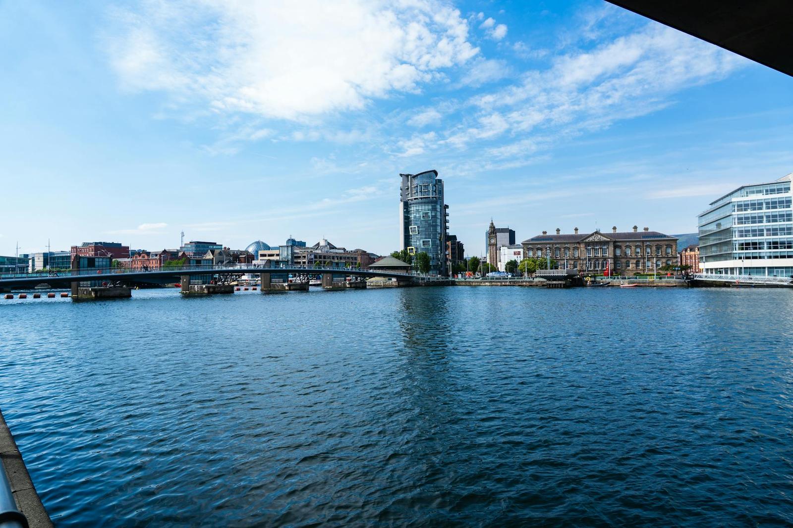 Riverside skyline with a low bridge and waterfront buildings under blue sky