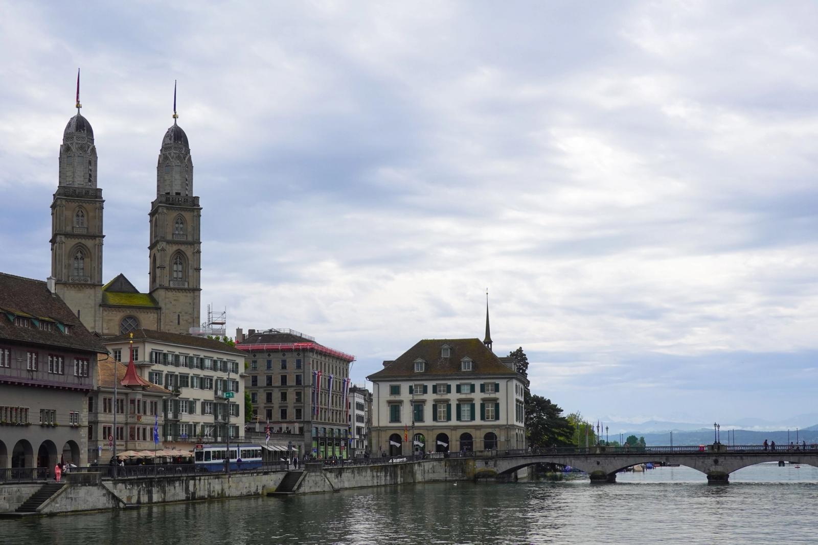 Beautiful cityscape of Zurich featuring Grossmünster along the Limmat River under a cloudy sky
