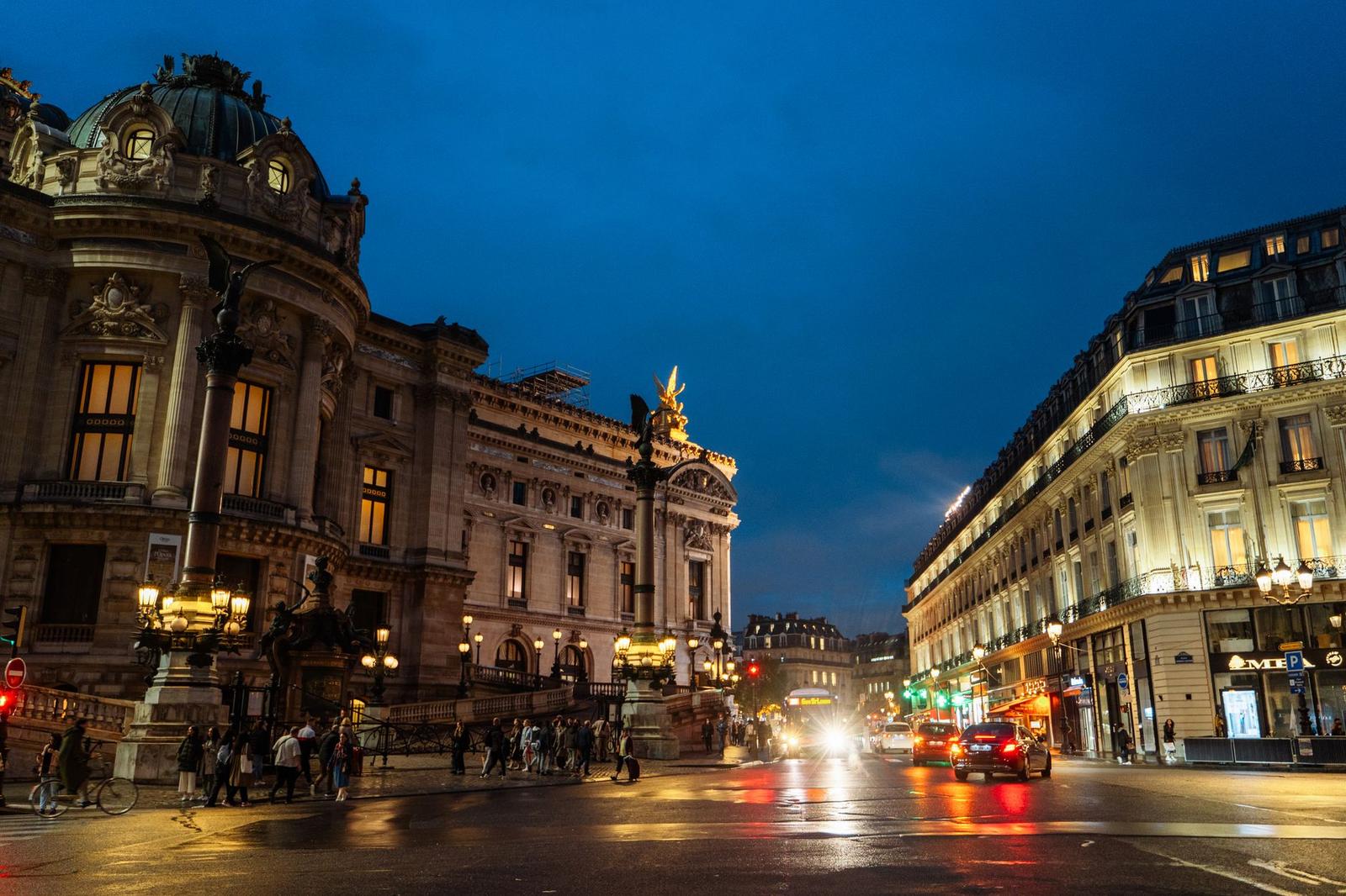 A grand ornate building lit up on a busy city street at night