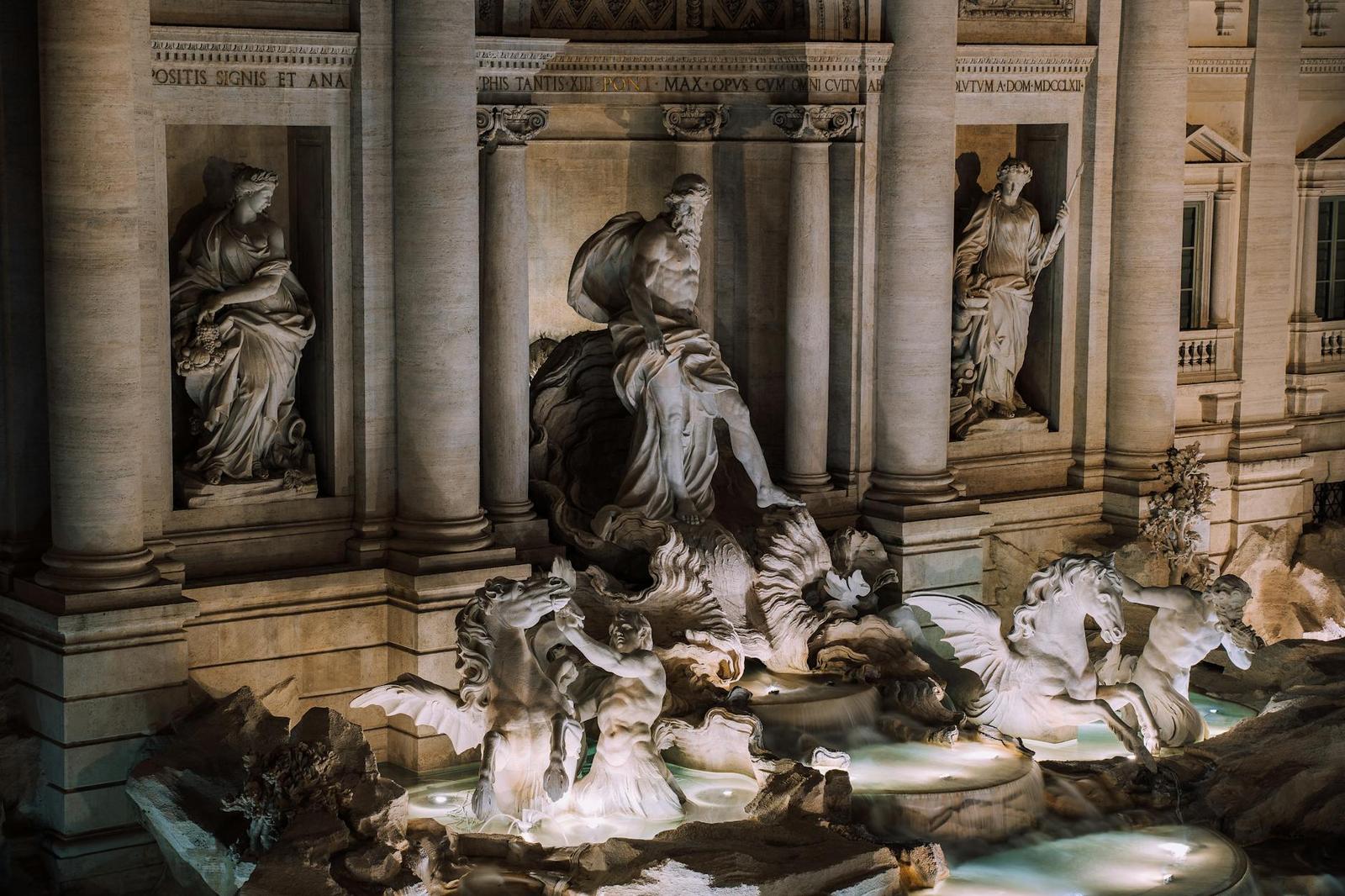 Illuminated statues and horses at the Trevi Fountain at night