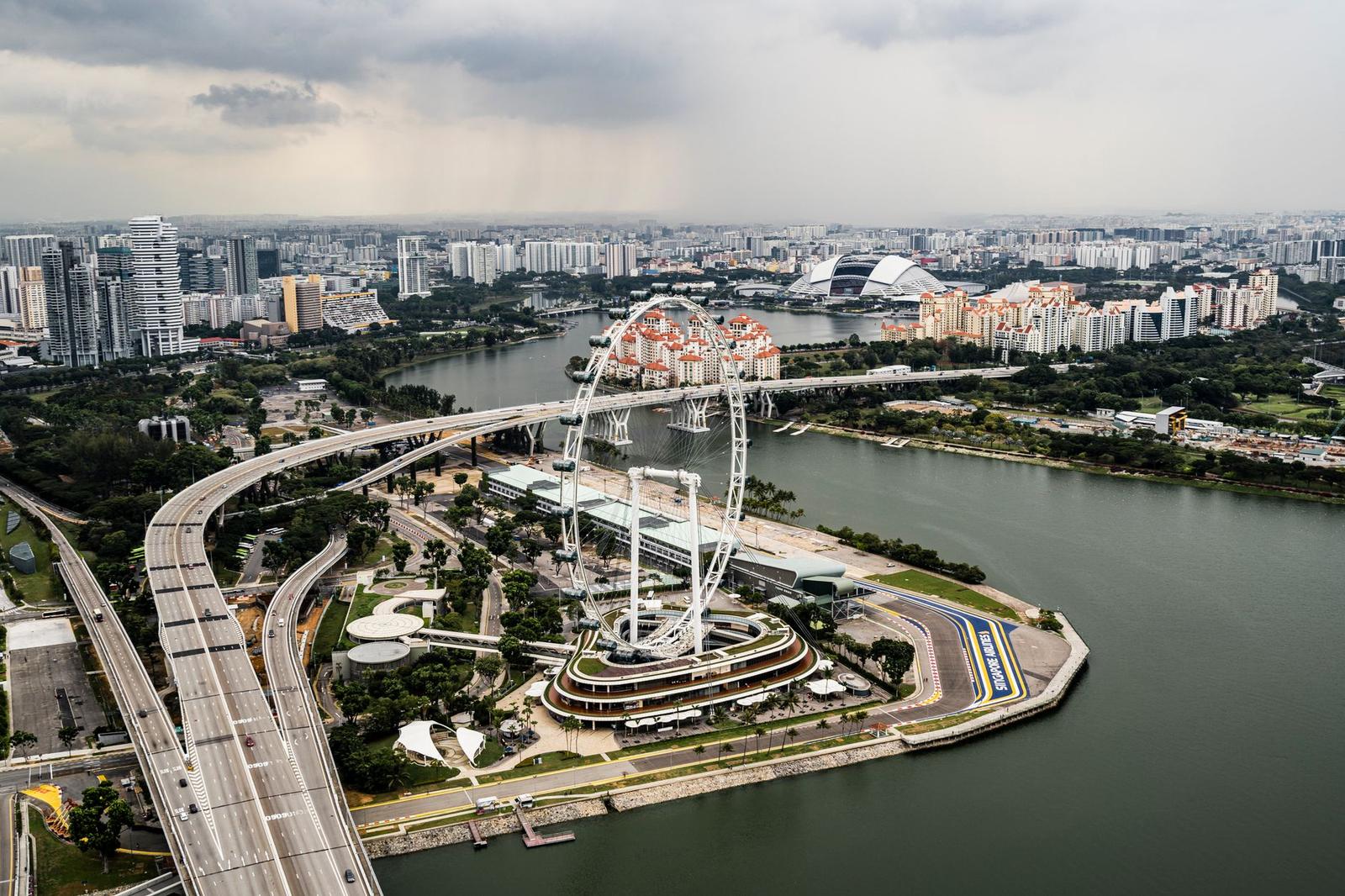 Aerial view of a giant observation wheel on a riverbank amid a green city park