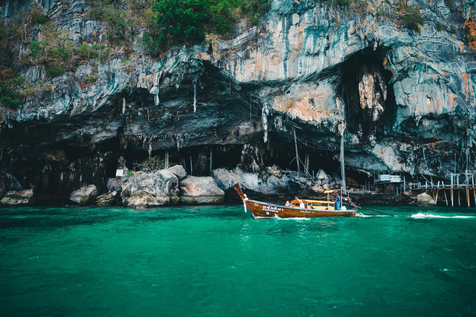 Explore the stunning limestone cliffs of Phuket with a traditional longtail boat on emerald waters