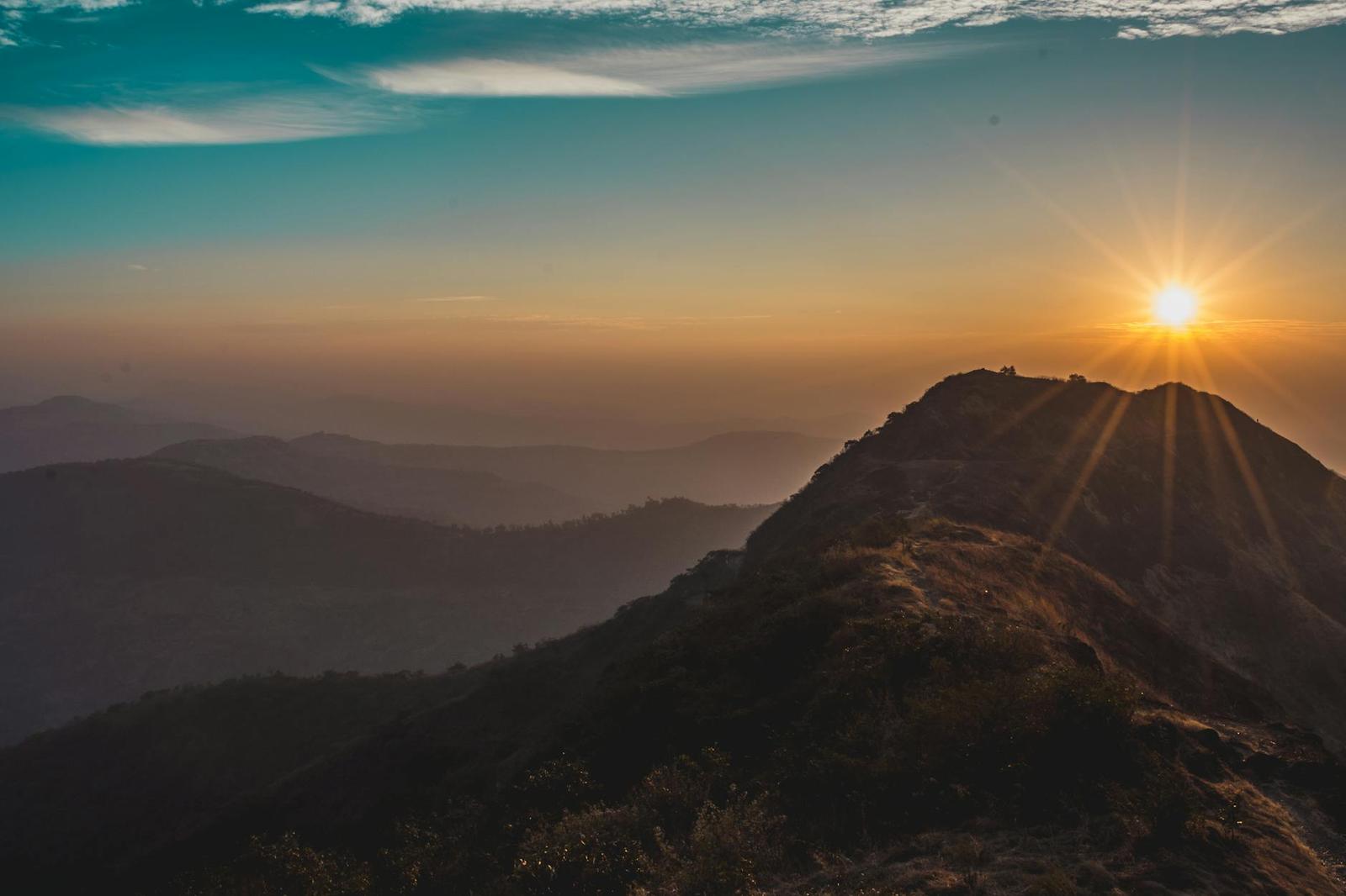 Sunburst breaking over a hilltop silhouette at dawn
