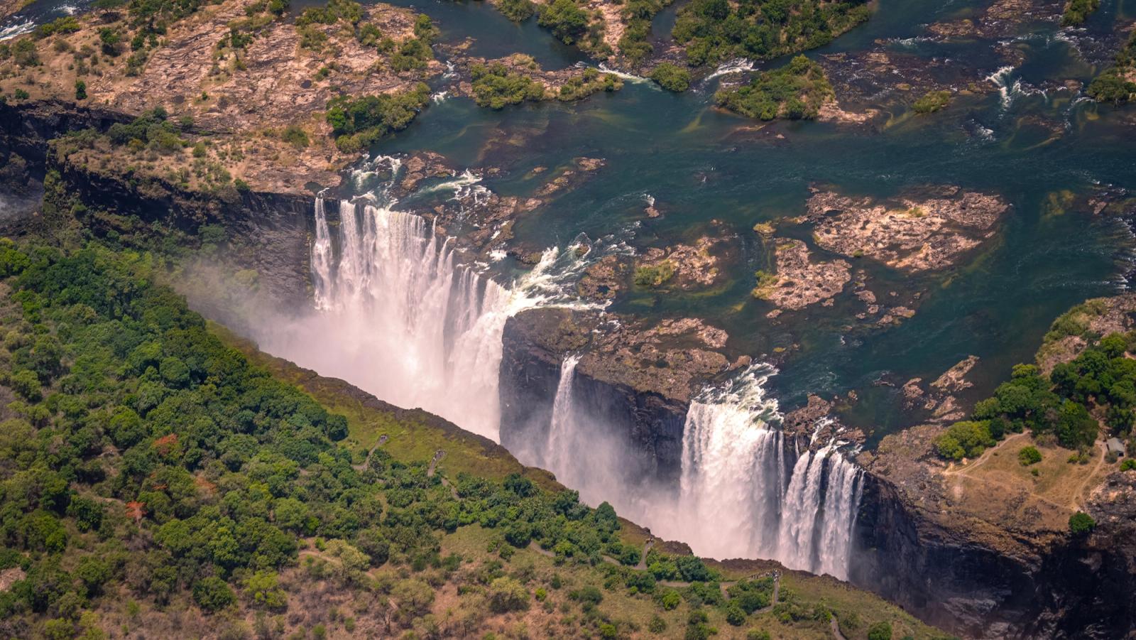 Sweeping aerial shot of a broad waterfall cascading through a rocky chasm
