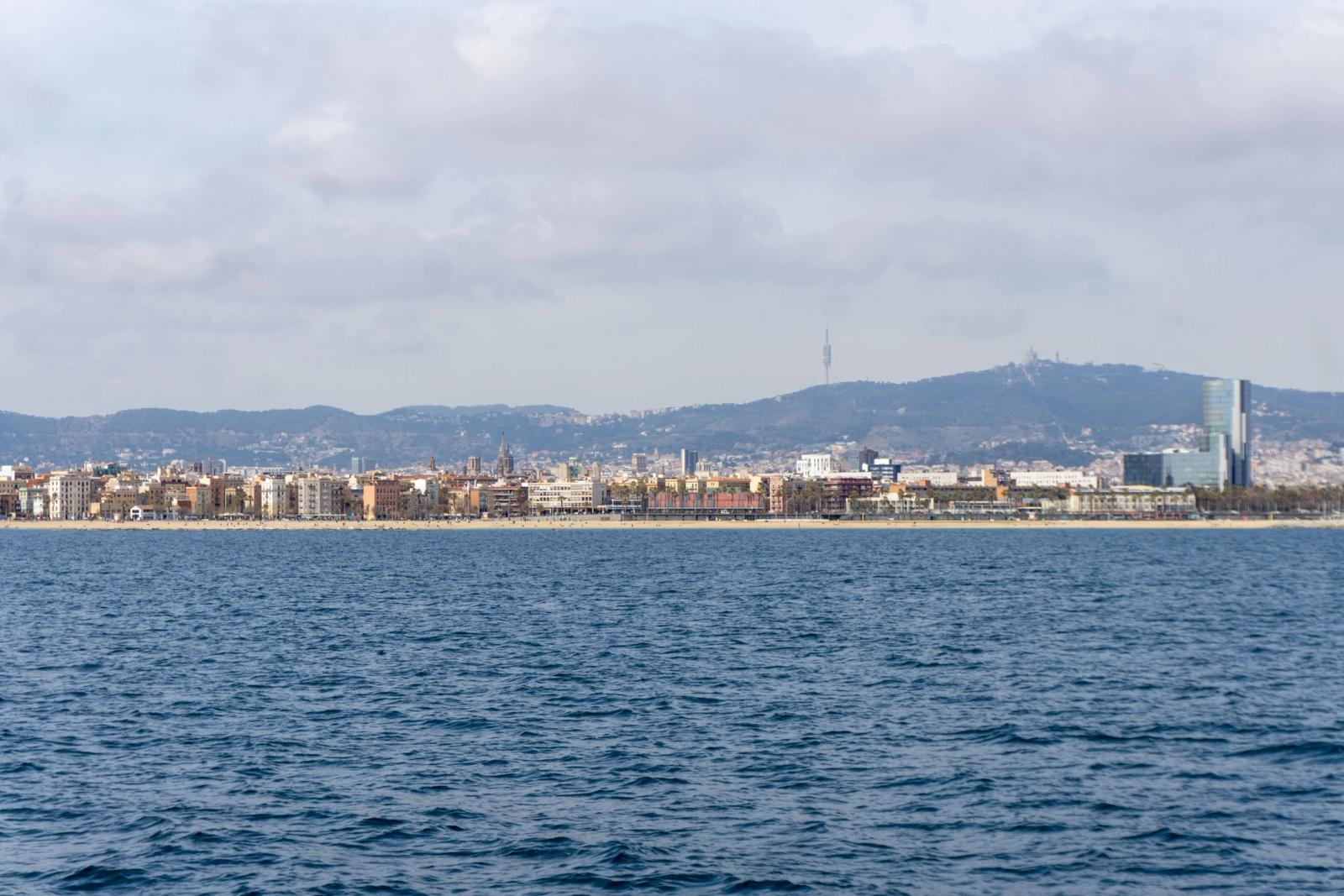 Stunning panoramic view of Barcelona coastline with urban skyline and distant hills under a cloudy sky