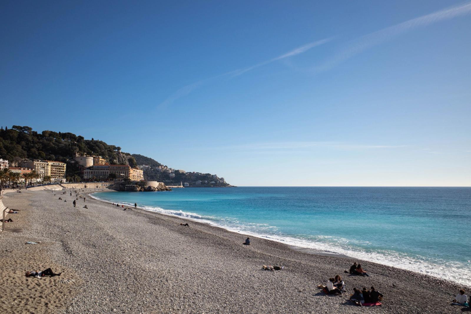 Tranquil beach scene in Nice, France with clear blue skies and lively coastline