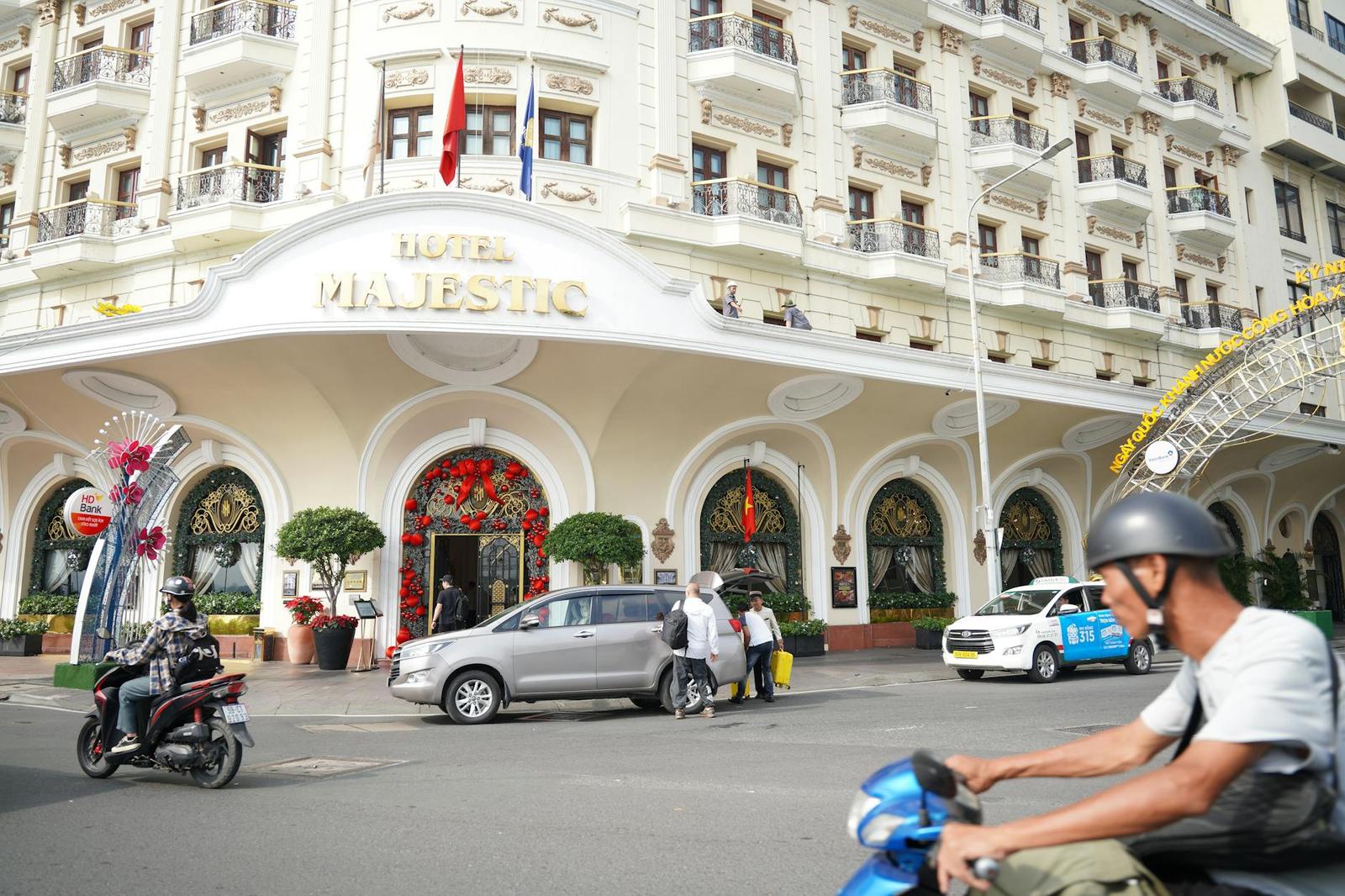 Grand colonial hotel facade with arched entrances and traffic passing in front