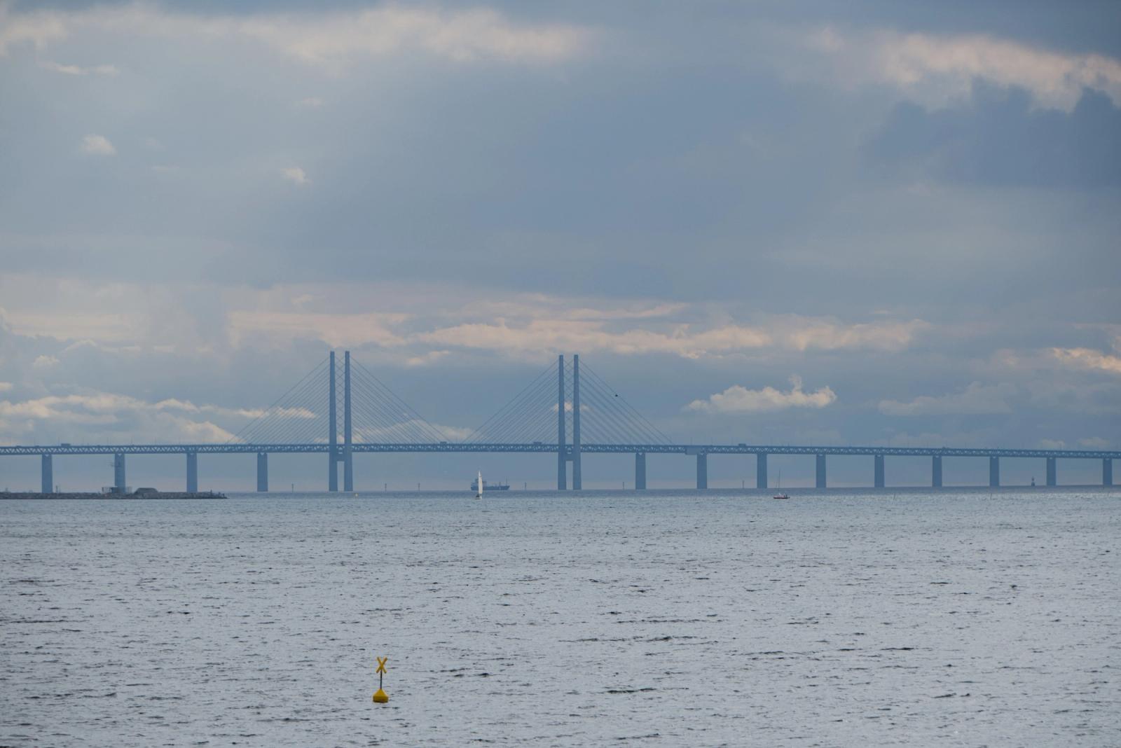 The Øresund Bridge spans across a serene sea under overcast skies, creating a breathtaking view