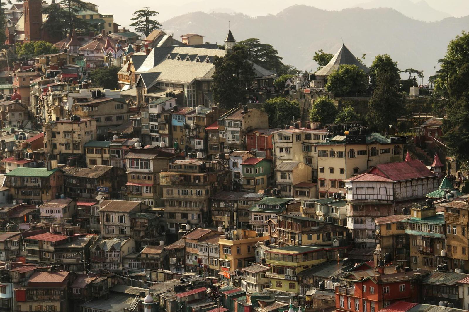 A hillside town of densely packed colorful buildings under distant peaks