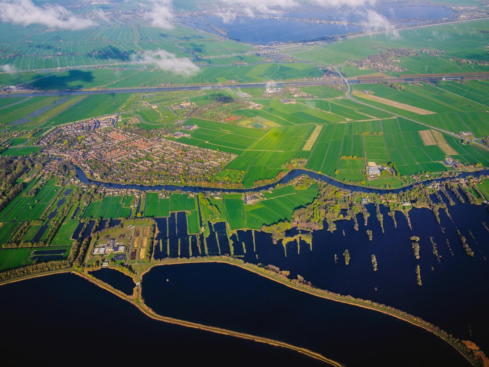 Aerial view of a patchwork of green fields threaded by winding waterways