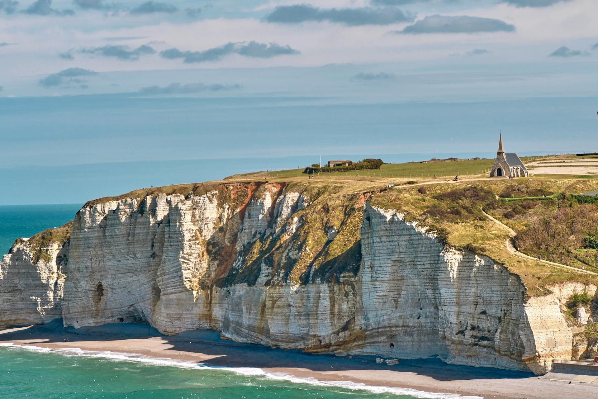 A small chapel perched atop white chalk cliffs overlooking the sea