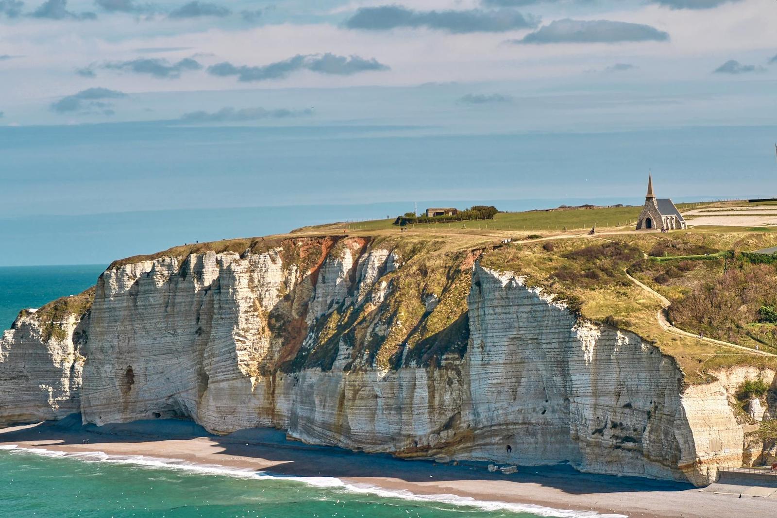 A small chapel perched atop white chalk cliffs overlooking the sea