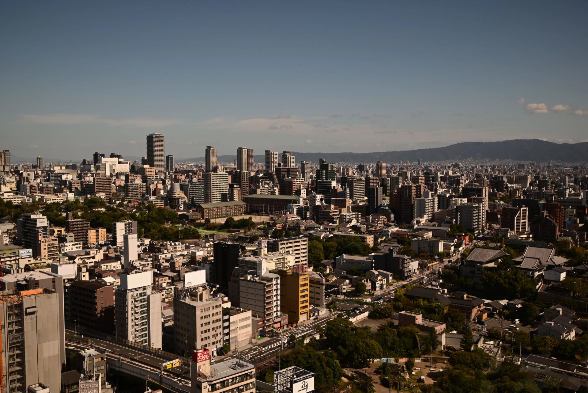 Stunning daytime aerial view of Osaka skyline showcasing urban architecture and distant hills