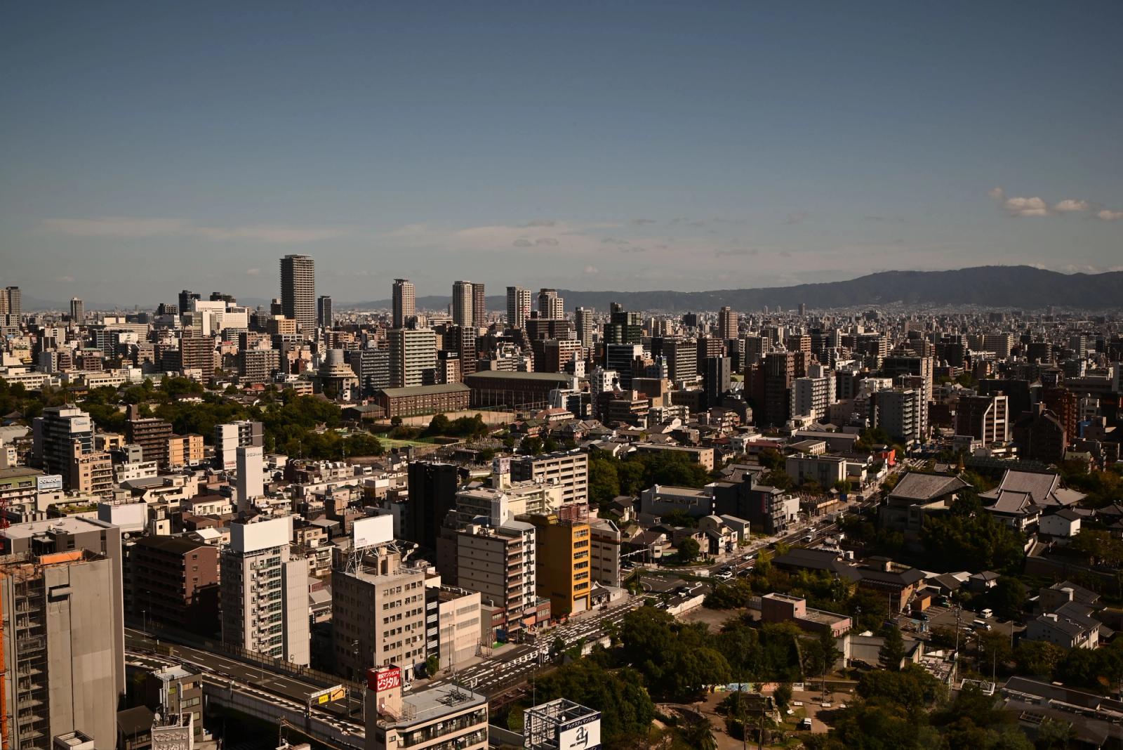 Stunning daytime aerial view of Osaka skyline showcasing urban architecture and distant hills