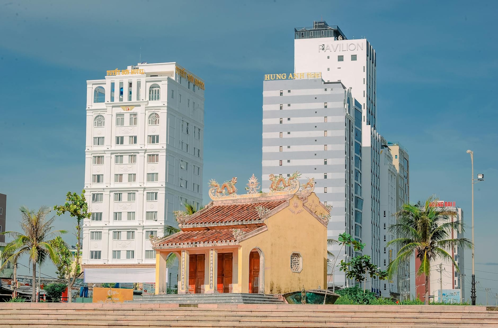 A small ornate pagoda framed by modern high-rise buildings behind it