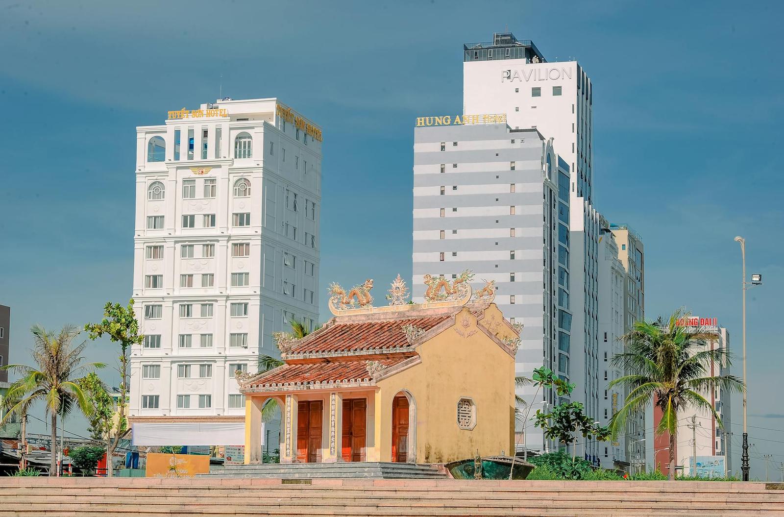 A small ornate pagoda framed by modern high-rise buildings behind it