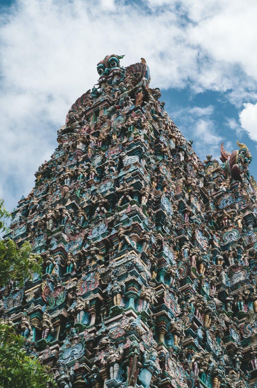Intricate carvings on a traditional Hindu temple tower under a bright blue sky