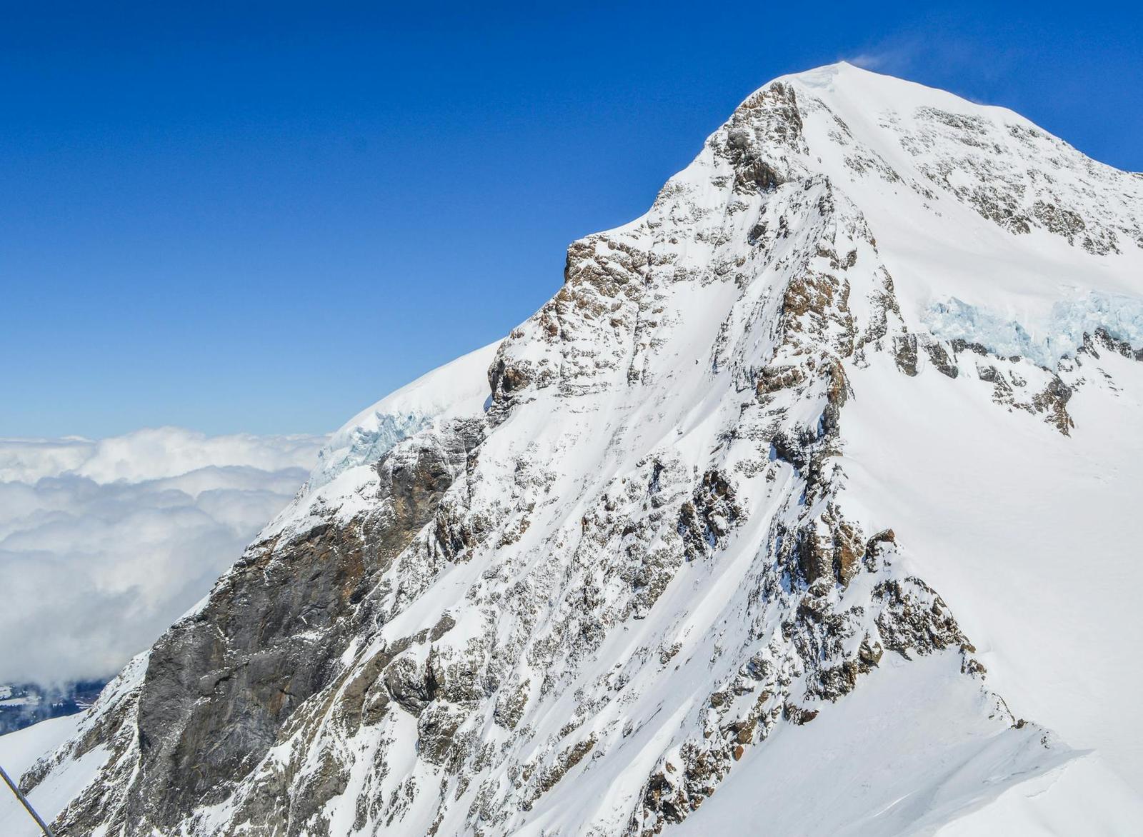Close-up of a rocky snow-covered mountain peak against a clear blue sky