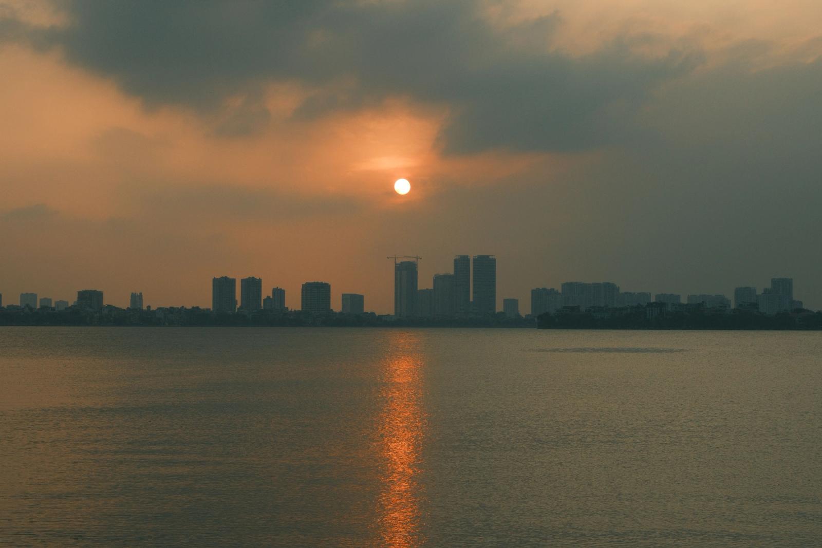 Calm sunset view of city skyline with sun reflection on water, Indore