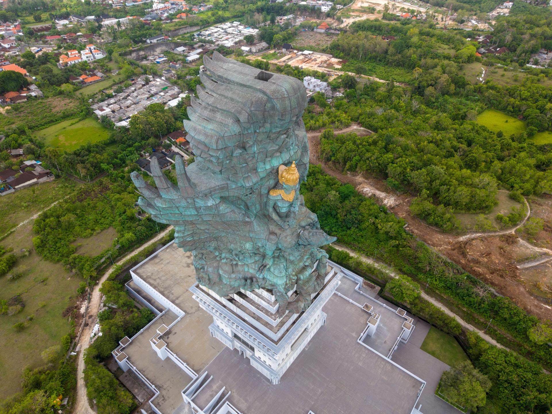 A striking aerial view of the Garuda Wisnu Kencana statue amidst lush greenery in Bali, Indonesia