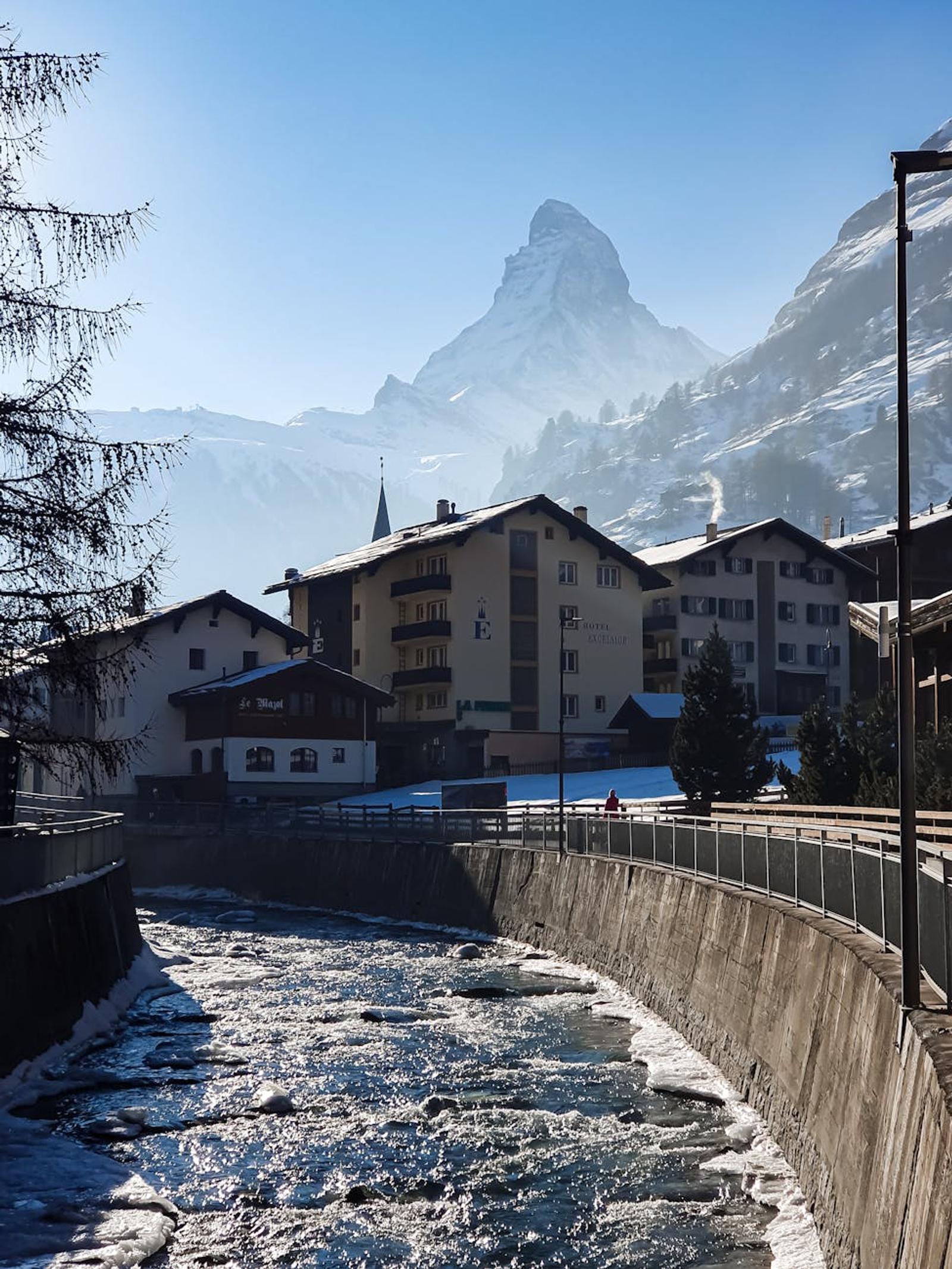 Icy stream running through a snowy village with a jagged peak beyond
