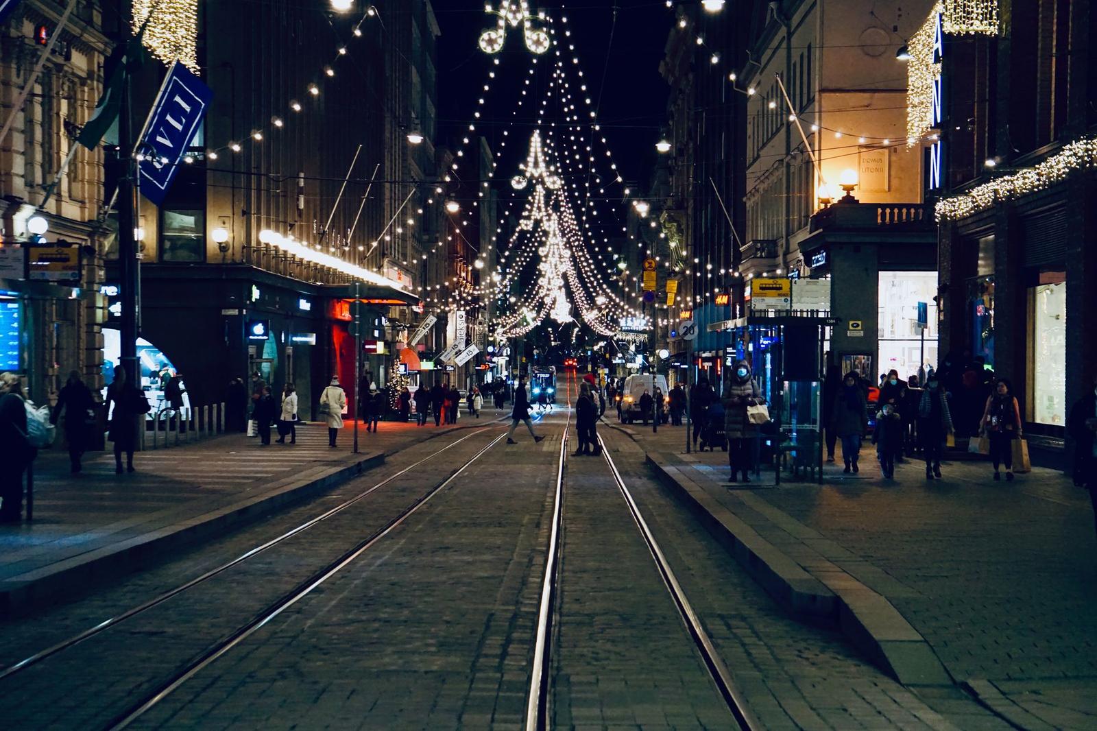 City street strung with festive lights above tram tracks at night
