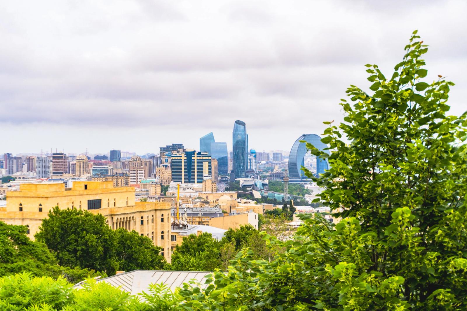 A vibrant view of Baku's skyline featuring modern architecture and lush greenery under a cloudy sky