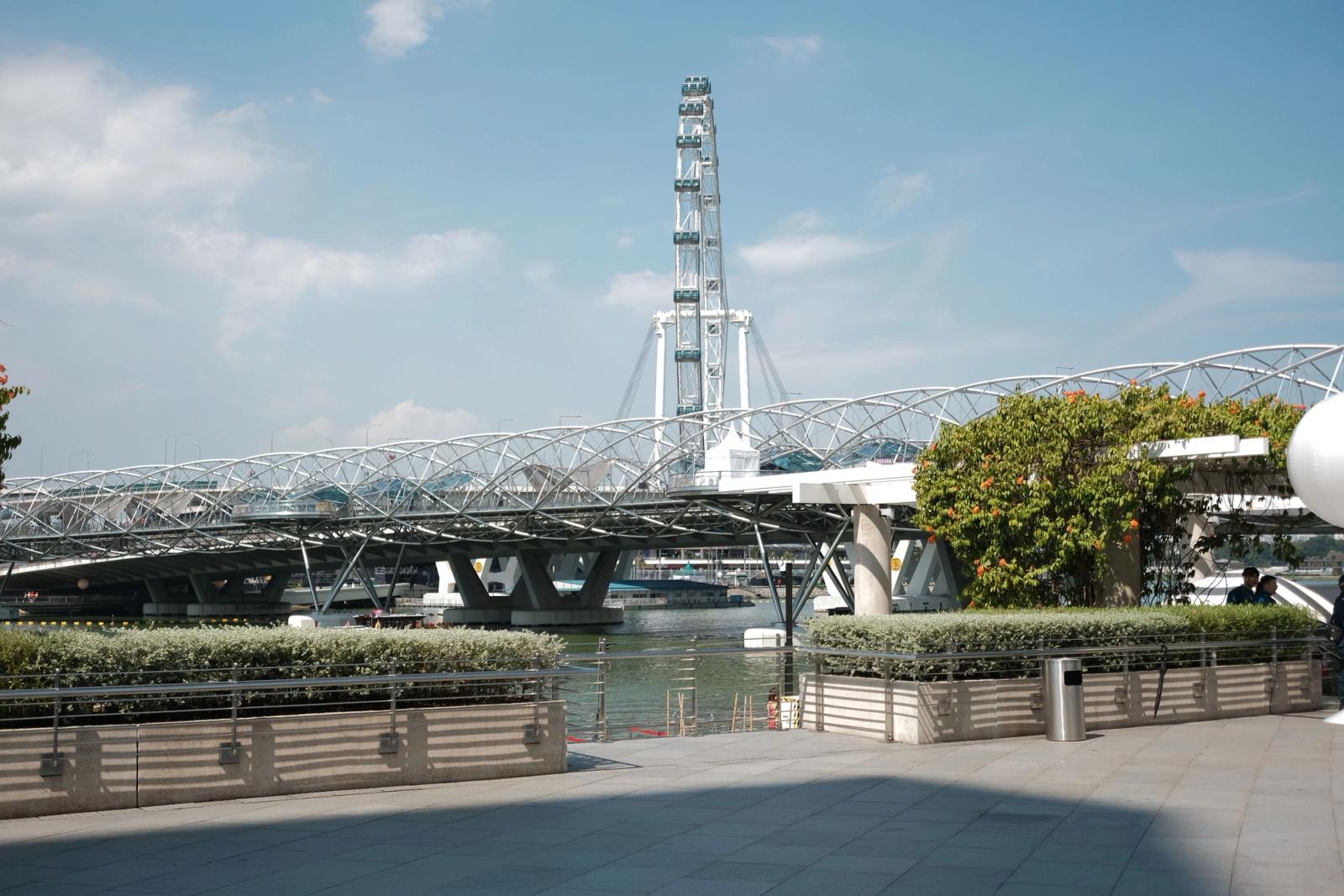 View of the Singapore Flyer and Helix Bridge with clear blue skies, showcasing modern architecture by the Marina Bay