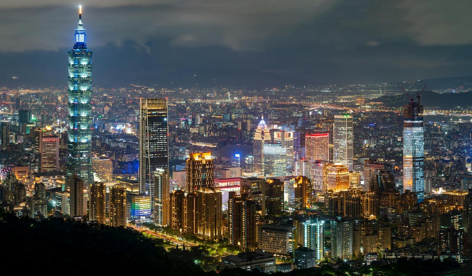 Illuminated skyscraper skyline seen from a hillside at night