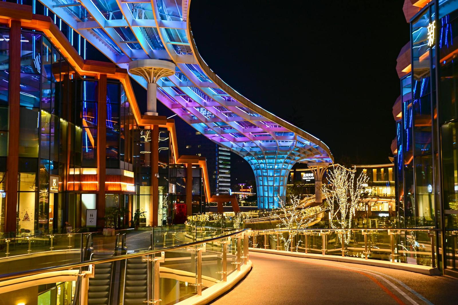 A futuristic covered walkway lit with blue and purple lights at night