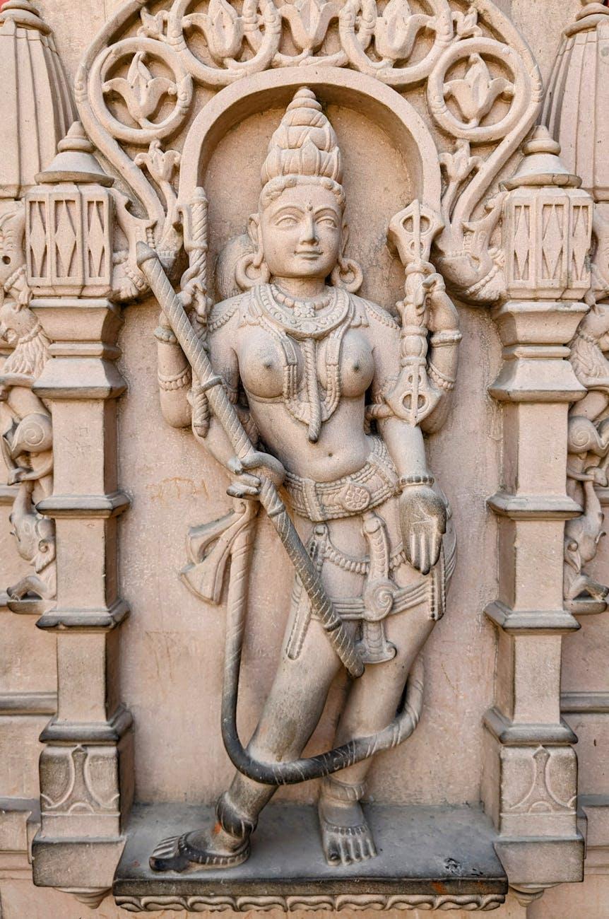 Carved stone relief of an ornately adorned deity figure in a temple niche