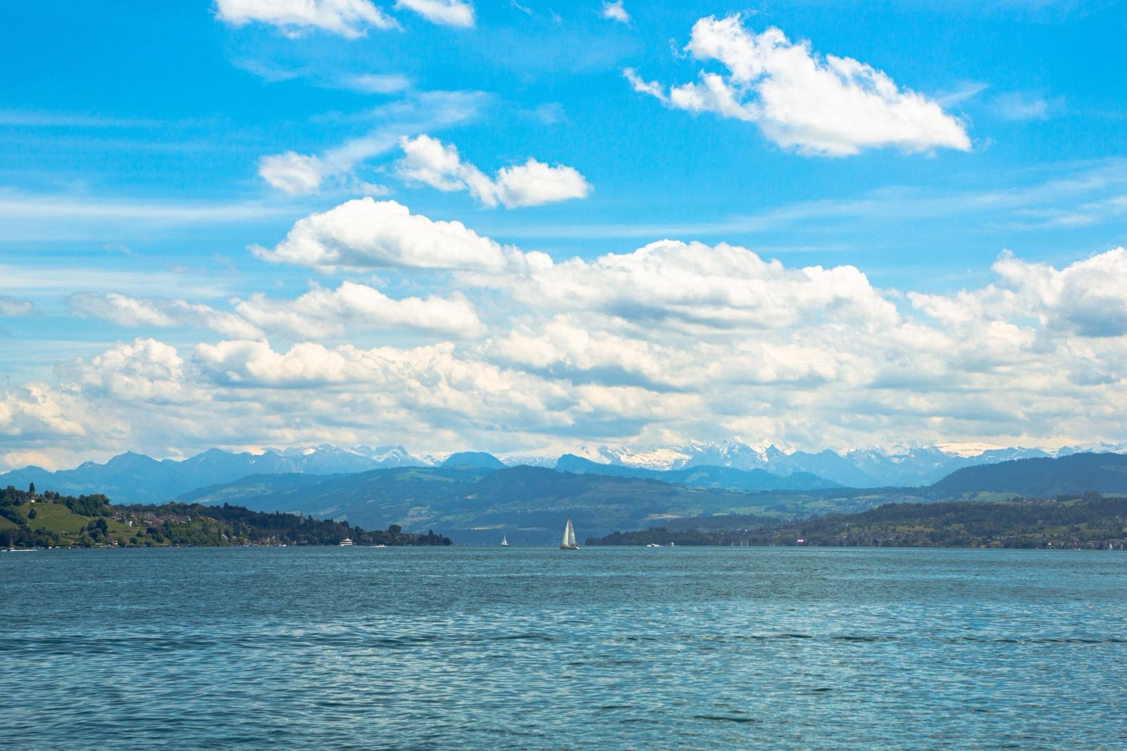 Beautiful view of Lake Zurich with the stunning Swiss Alps in the background, under a bright blue sky