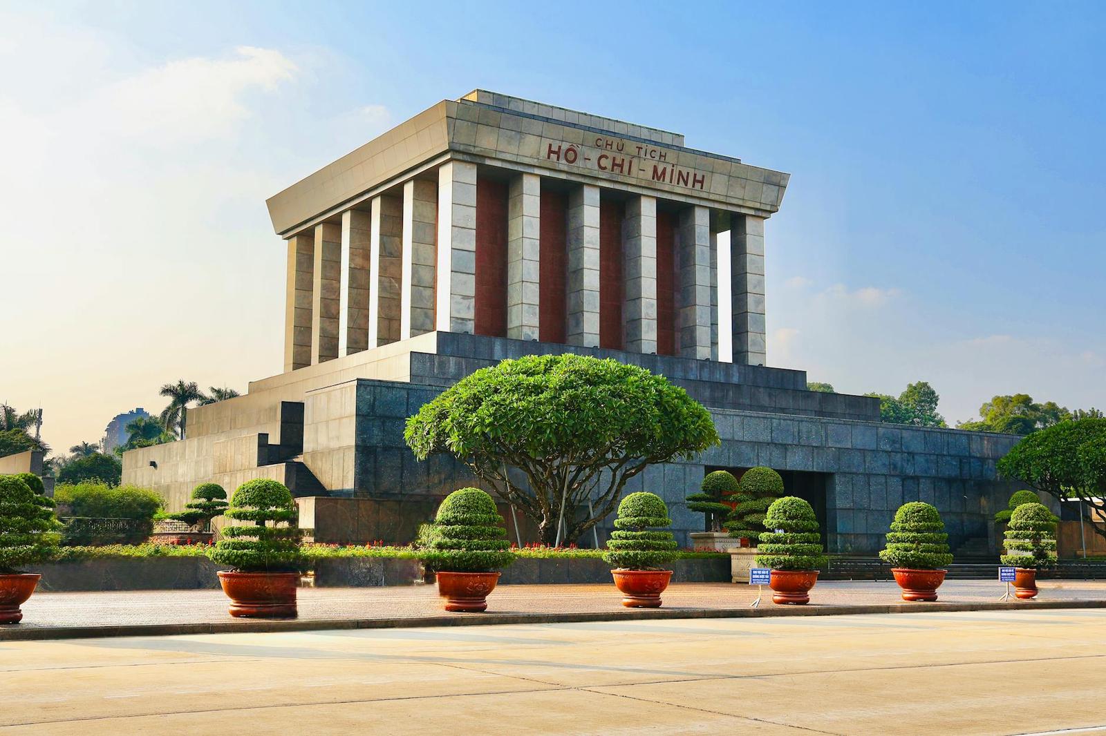 Grand stone mausoleum with fluted columns and rows of manicured bonsai trees