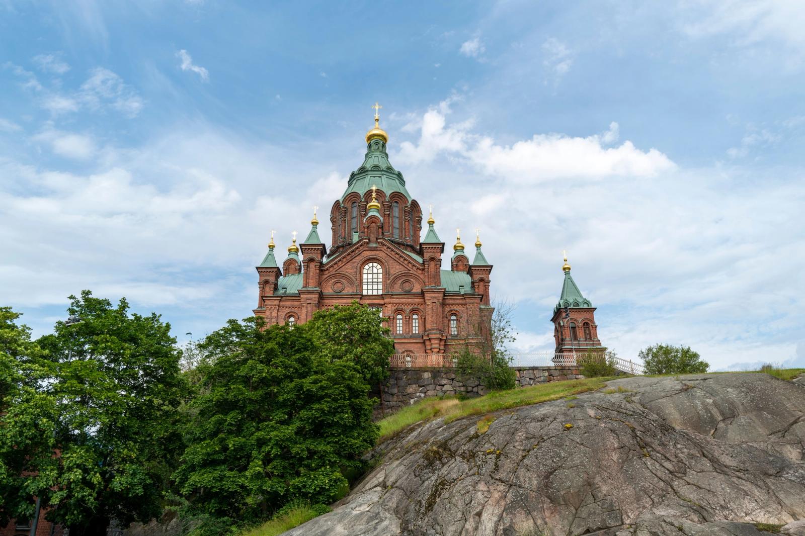 Majestic Uspenski Cathedral in Helsinki, Finland, against a clear blue sky, showcasing vibrant architecture