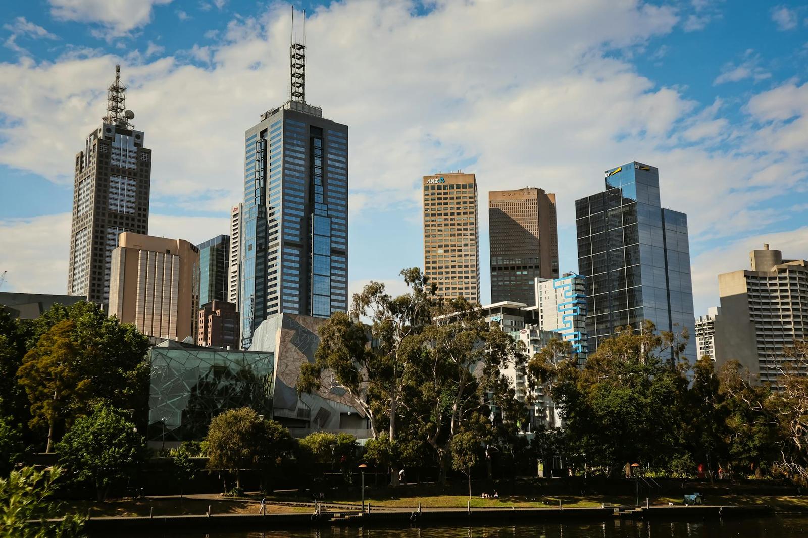 City skyscrapers rise behind riverside parkland and trees