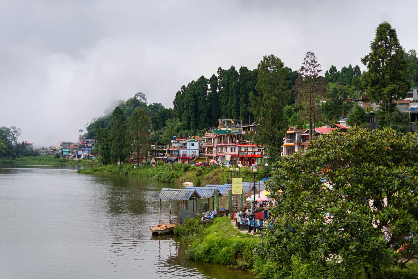 Picturesque view of Mirik Lake surrounded by lush greenery and misty mountains in West Bengal, India