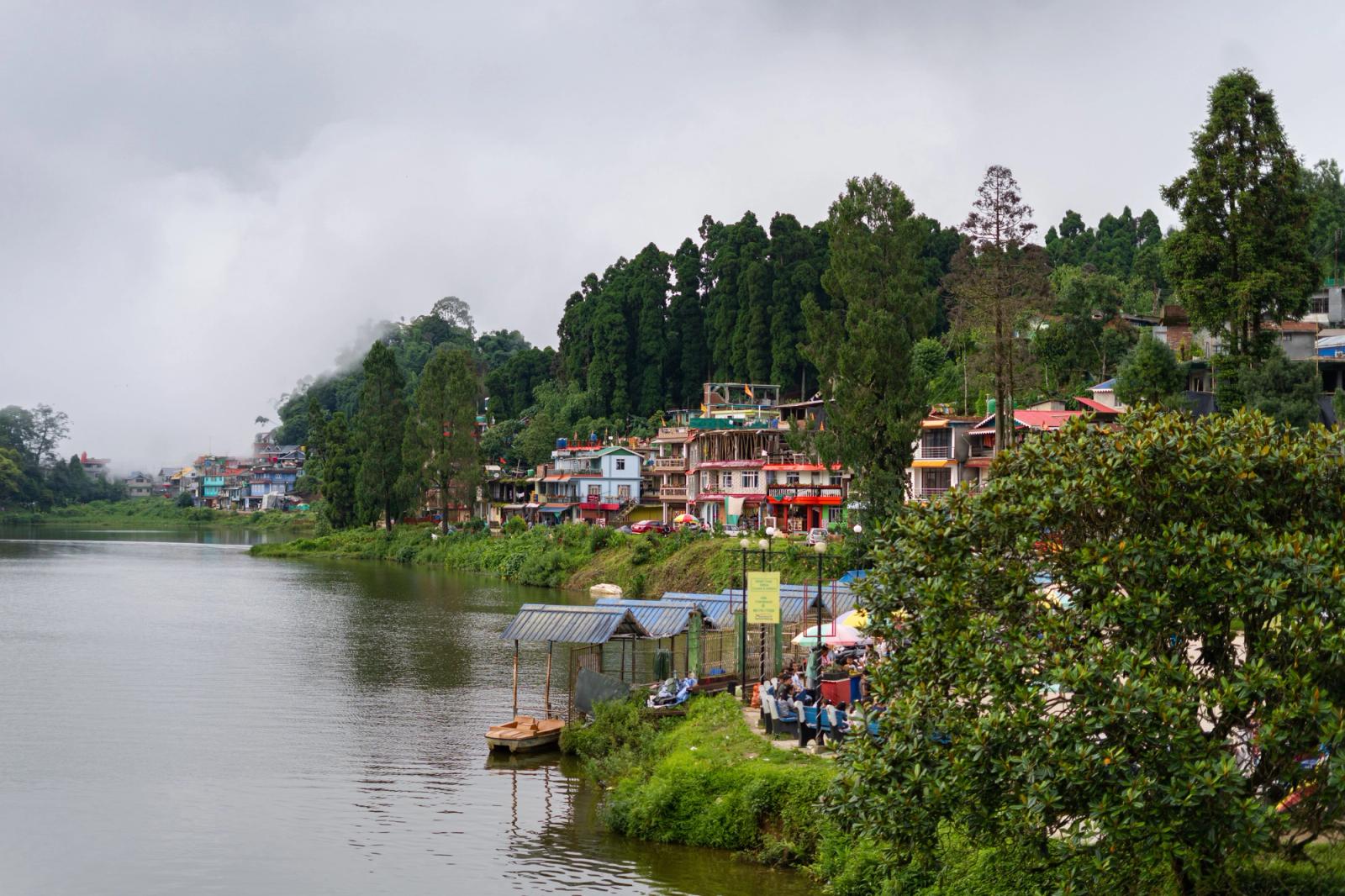 Picturesque view of Mirik Lake surrounded by lush greenery and misty mountains in West Bengal, India