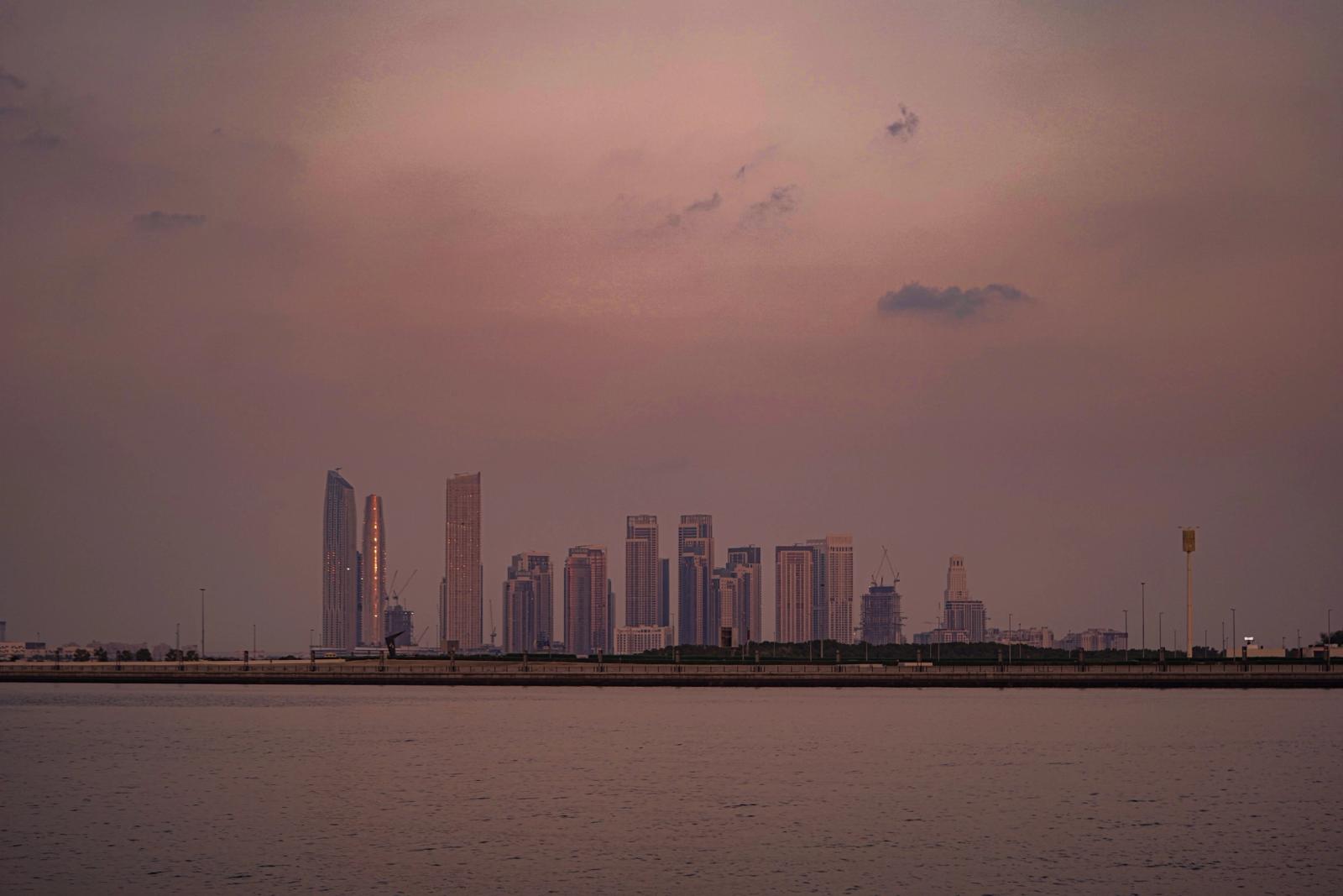 Stunning view of Dubai's skyline at dusk, featuring tranquil sea and skyscrapers