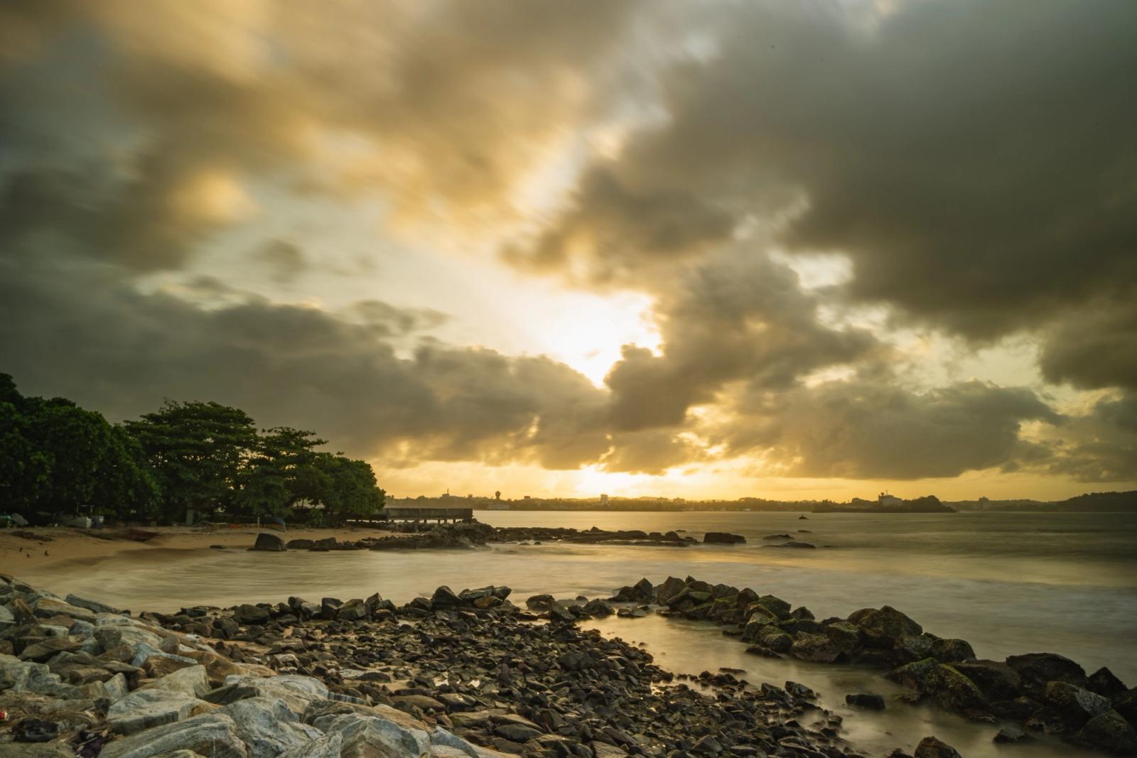 Dramatic sunset over rocky shores at Galle Beach, Sri Lanka