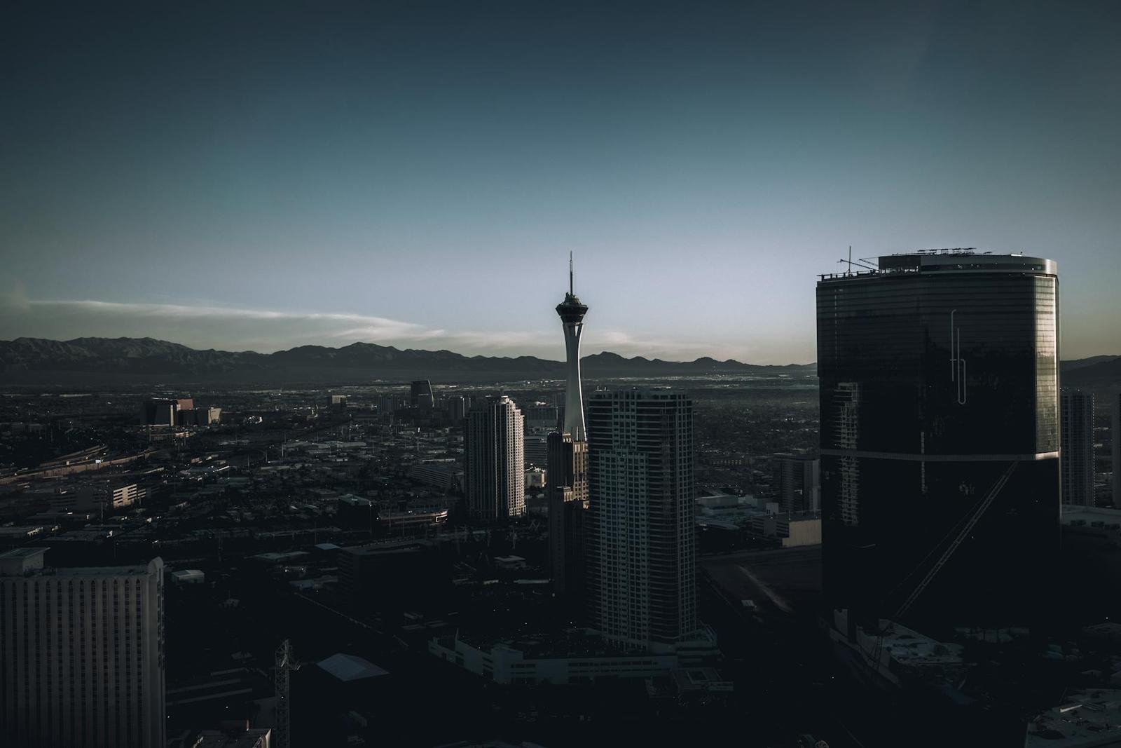 A slender observation tower rising above city skyscrapers at dusk