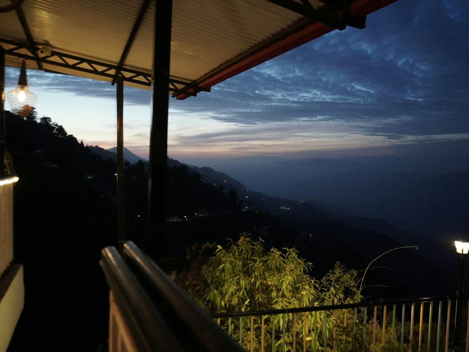 A hill-station terrace at dusk over the valley lights