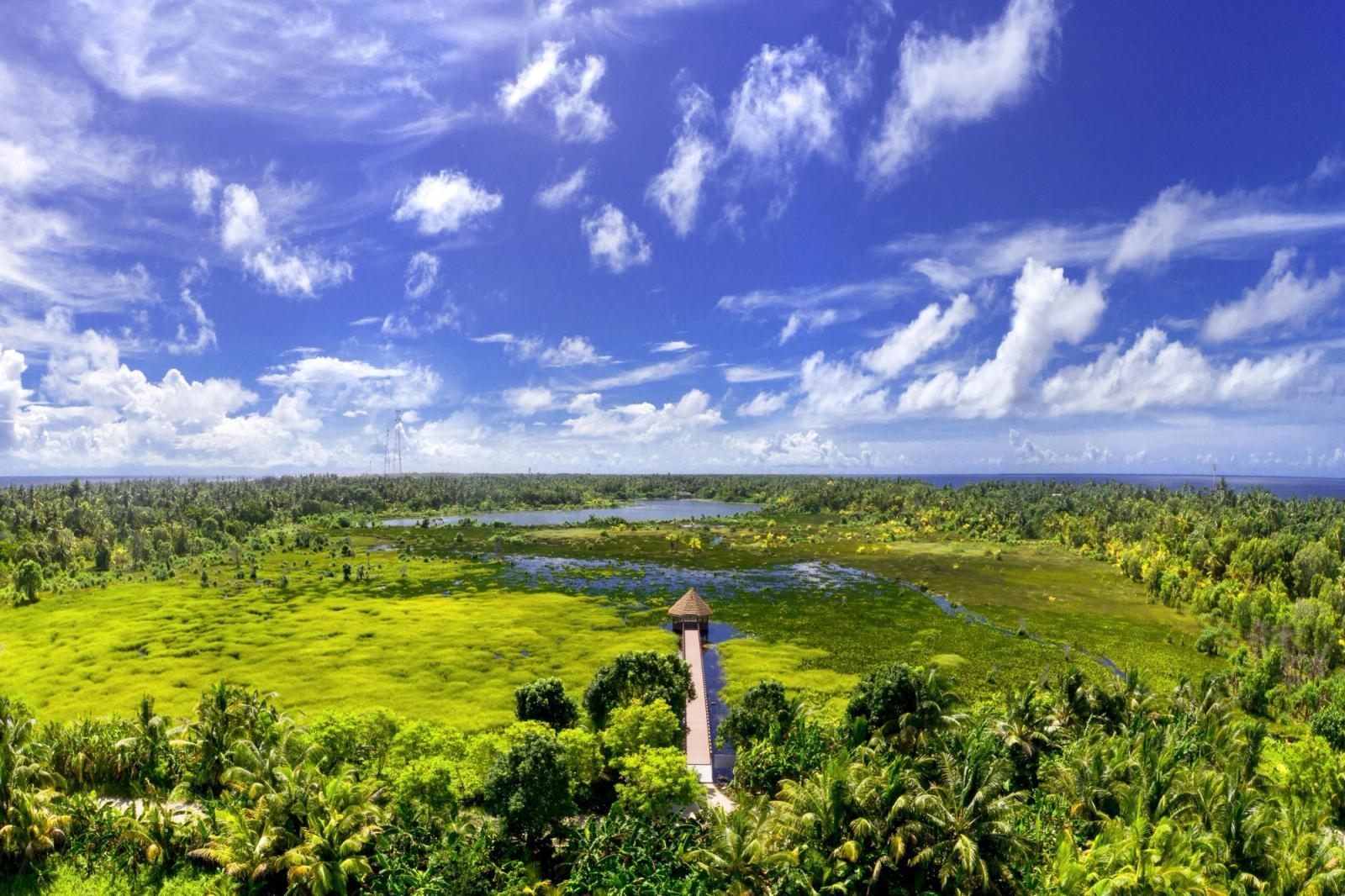 A stunning aerial view of Fuvahmulah, Maldives showcasing lush greenery, blue skies, and tropical beauty